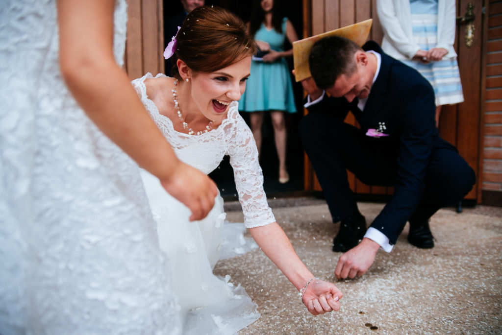 poradnik ślubny - niezbędnik gościa weselnego - zdjęcie przedstawia parę młodą zbierającą monety. Jest to nieodłączny element w przebiegu ślubu kościelnego, choć nie jest pochwalany przez Kościół Katolicki.